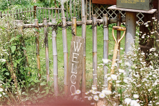 A welcome sign on a rustic garden tool fence