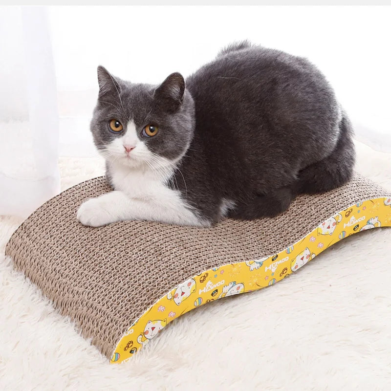 A gray and white cat resting on a corrugated cardboard scratching pad.